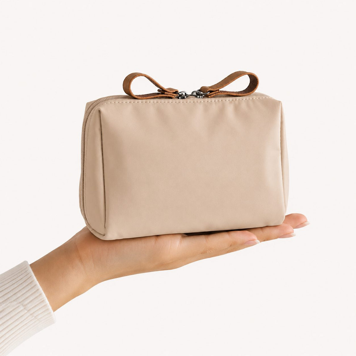 Beige toilettaske i nylon, der holdes i hånden