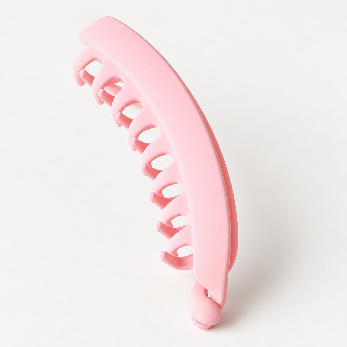 Rosa bananklämma med tandad kant på ljust underlag