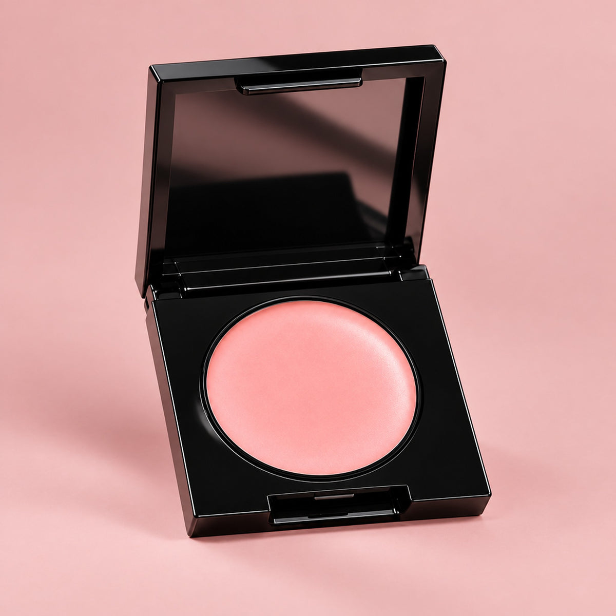 Öppen svart kompakt med rosa concealerkräm och spegel