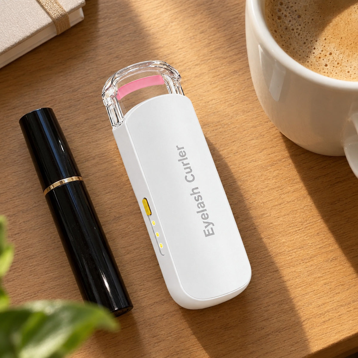 Fransböjare på skrivbord bredvid mascara och kaffekopp